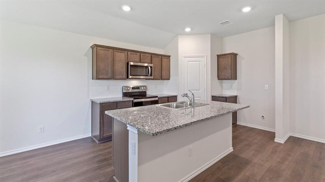 Kitchen featuring an island with a dual-basin sink and a high-arc faucet, granite countertops, wood-finish flooring, recessed lighting, and stainless steel appliances