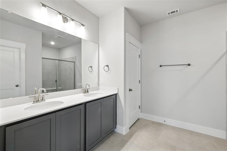 Full bathroom with a stall shower, double vanity, and light tile patterned flooring
