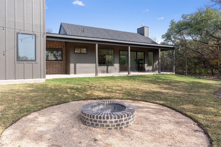 A private backyard setting with a built-in fire pit and covered patio, ideal for relaxing evenings and gathering under the trees. A private backyard setting with a built-in fire pit and covered patio, ideal for relaxing evenings and gathering under the trees.