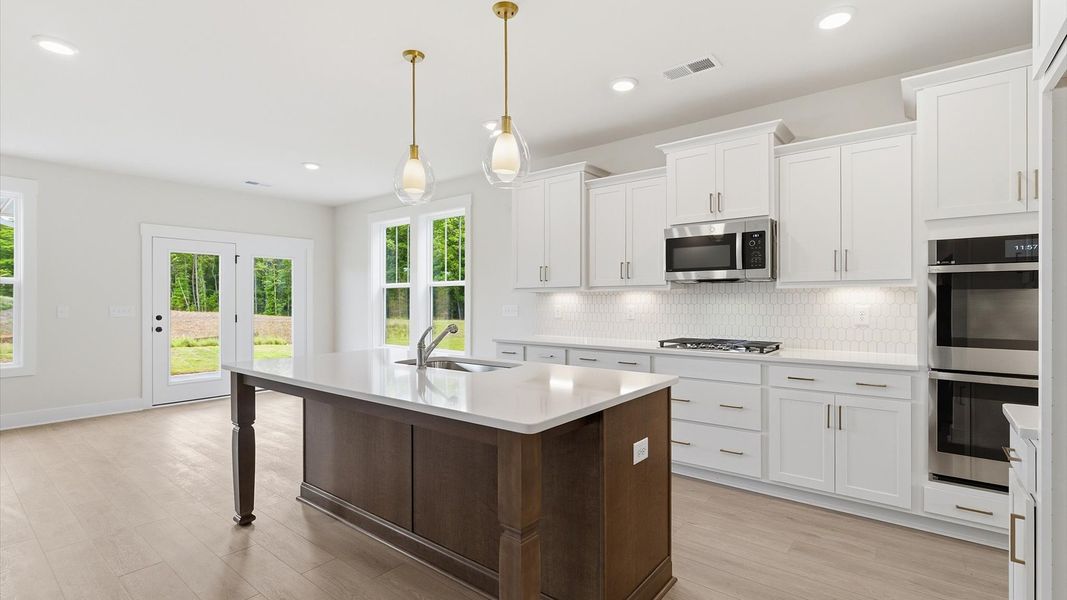 Highly skilled craftsmanship shines in this modern kitchen with pendant lighting and a central island focal point