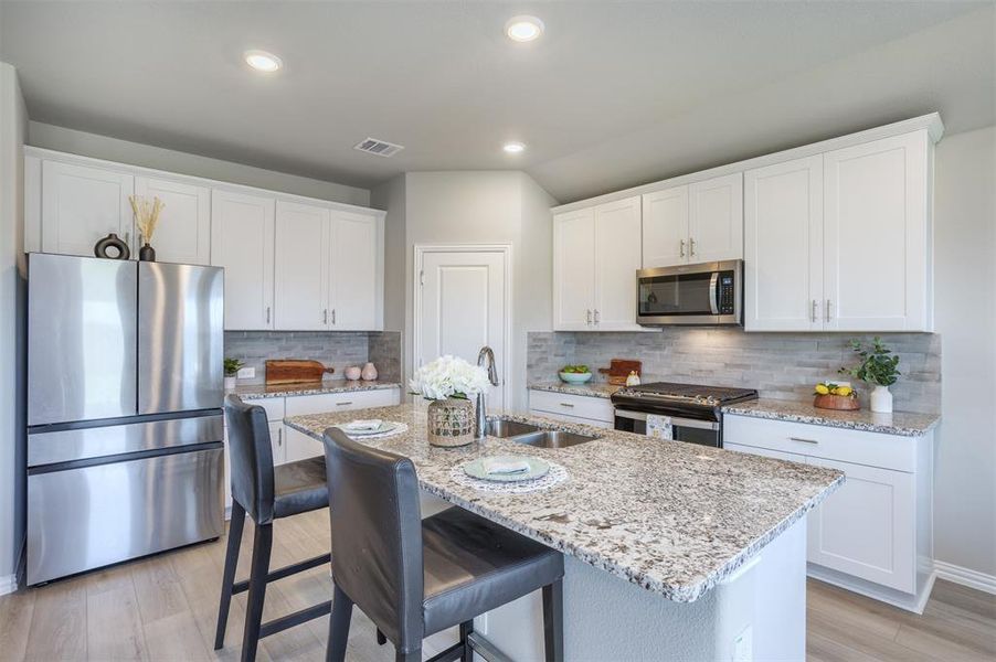 Kitchen with appliances with stainless steel finishes, an island with sink, white cabinets, and recessed lighting Kitchen with appliances with stainless steel finishes, an island with sink, white cabinets, and recessed lighting