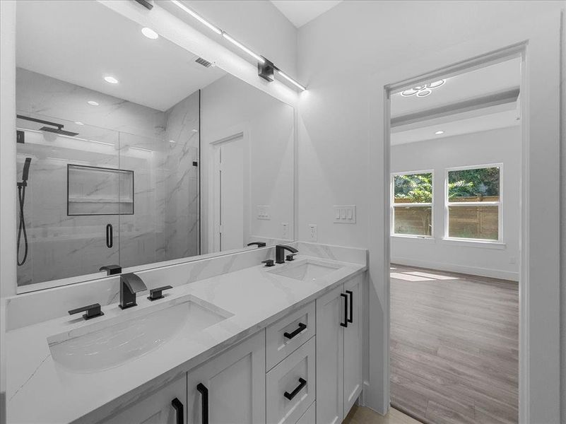Full bath featuring double vanity, a marble finish shower, recessed lighting, and light wood-style floors Full bath featuring double vanity, a marble finish shower, recessed lighting, and light wood-style floors
