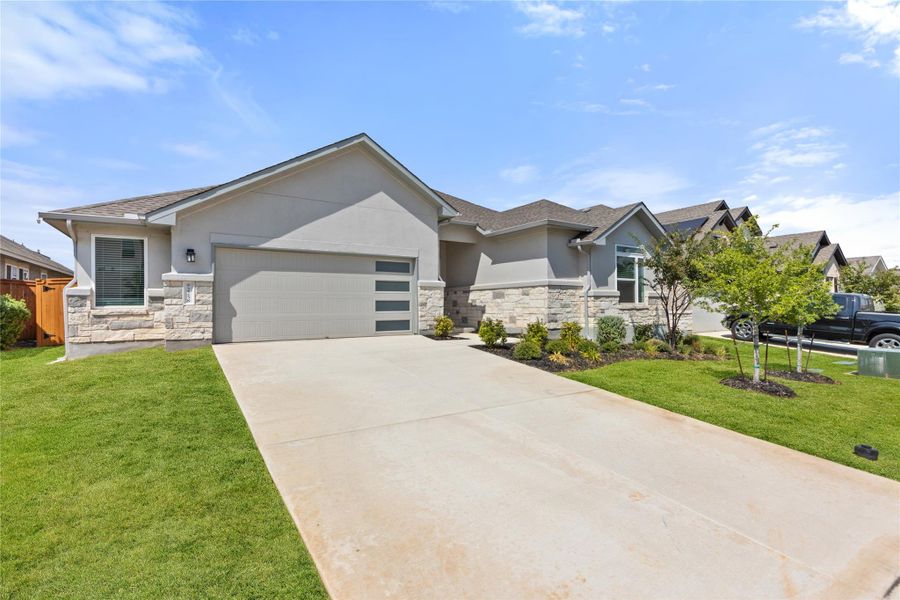 View of front of property with stone siding, stucco siding, an attached garage, and driveway
