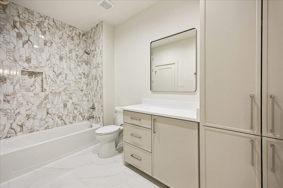 Designer finishes make this upstairs bathroom feel anything but ordinary, with stunning tile work, a sleek vanity and custom storage solutions that keep everyday essentials neatly tucked away.