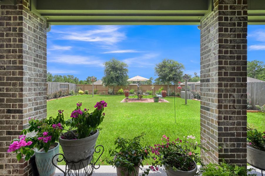 Enjoy peaceful outdoor living from the covered patio overlooking a beautifully landscaped, fully fenced backyard featuring lush green space, decorative garden beds, and a charming patio seating area perfect for relaxing or entertaining. Enjoy peaceful outdoor living from the covered patio overlooking a beautifully landscaped, fully fenced backyard featuring lush green space, decorative garden beds, and a charming patio seating area perfect for relaxing or entertaining.