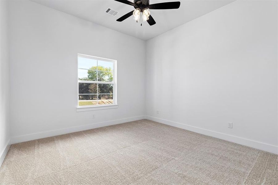 Empty room with ceiling fan and light colored carpet