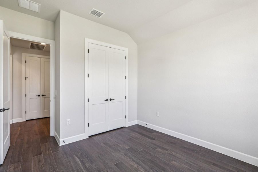 Unfurnished bedroom featuring dark wood-style flooring and a closet Unfurnished bedroom featuring dark wood-style flooring and a closet