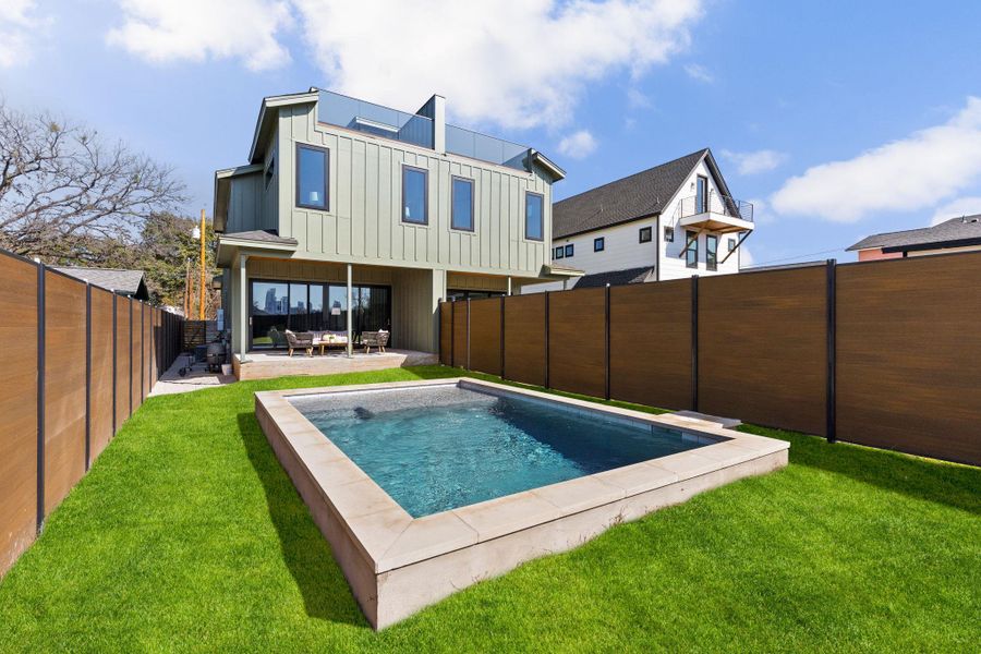 Rear view of property featuring board and batten siding, a patio, and a fenced backyard