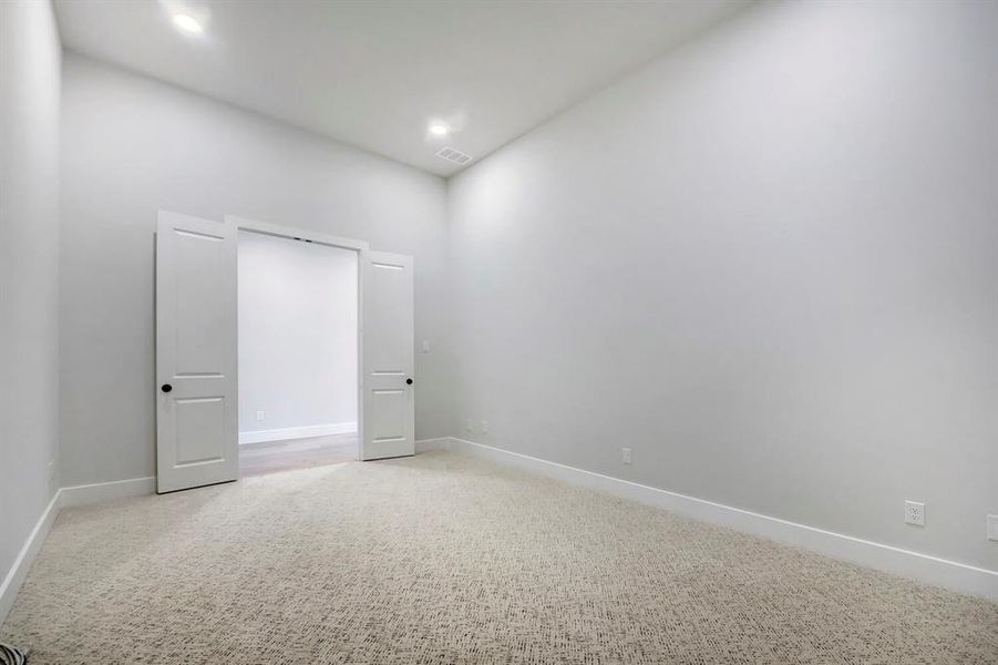 Carpeted room with high ceilings, recessed lighting, and a neutral wall palette