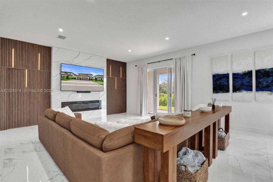 Spacious living area featuring large format floor tiling, a decorative electric fireplace, and a striking accent wall with integrated vertical lighting