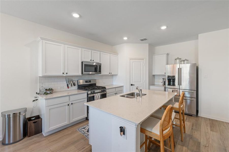 Kitchen featuring light hardwood / wood-style floors, stainless steel appliances, and white cabinets