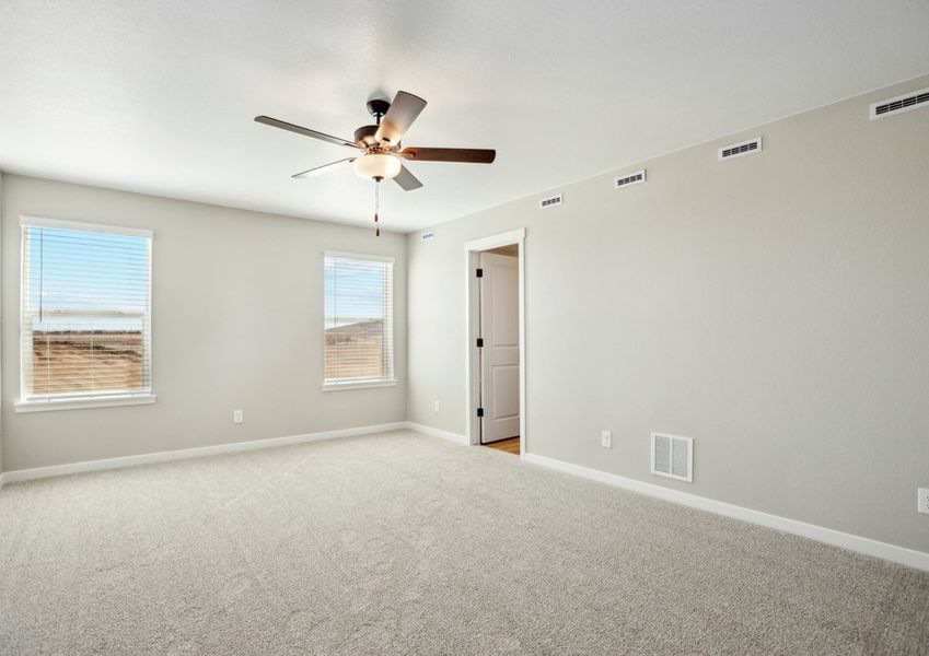 The master bedroom is spacious and has a ceiling fan.