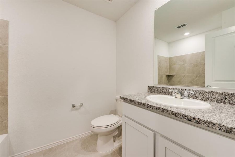 Bathroom featuring tile patterned flooring, toilet, and vanity