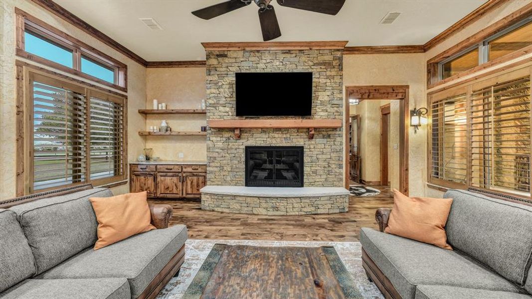 Floor-to-ceiling stone surround with wood mantle, built-in cabinetry, and shelving for display and storage.