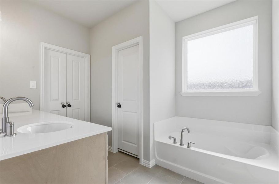 Full bathroom with vanity, a garden tub, and light tile patterned flooring Full bathroom with vanity, a garden tub, and light tile patterned flooring
