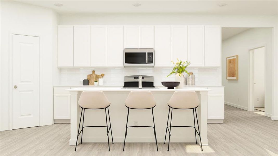 Kitchen with white cabinets, stainless steel appliances, an island with sink, and light hardwood / wood-style flooring