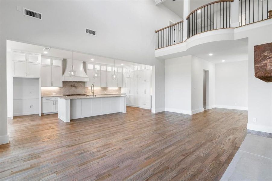 Unfurnished living room featuring a towering ceiling and light wood-type flooring