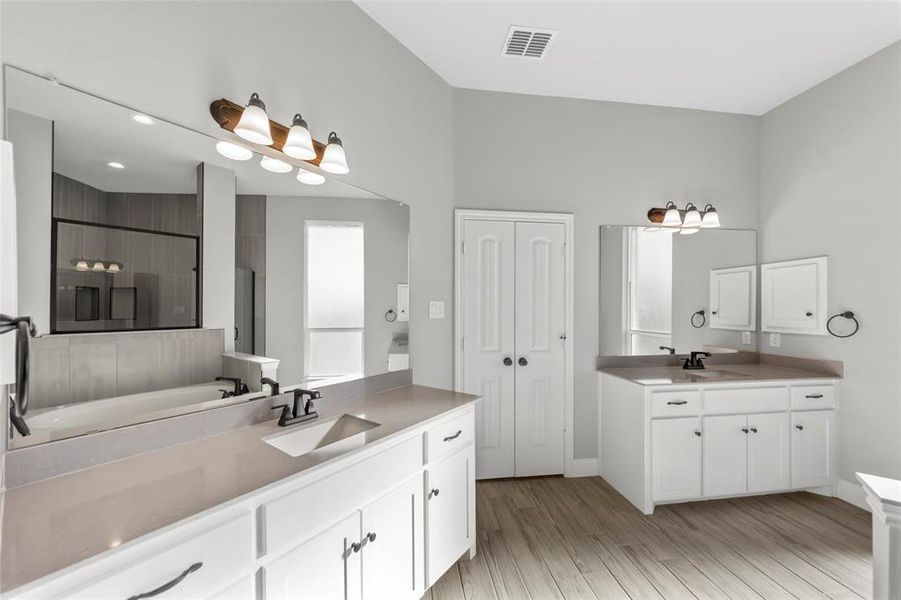 Bathroom with vanity, a shower with shower door, and wood-type flooring