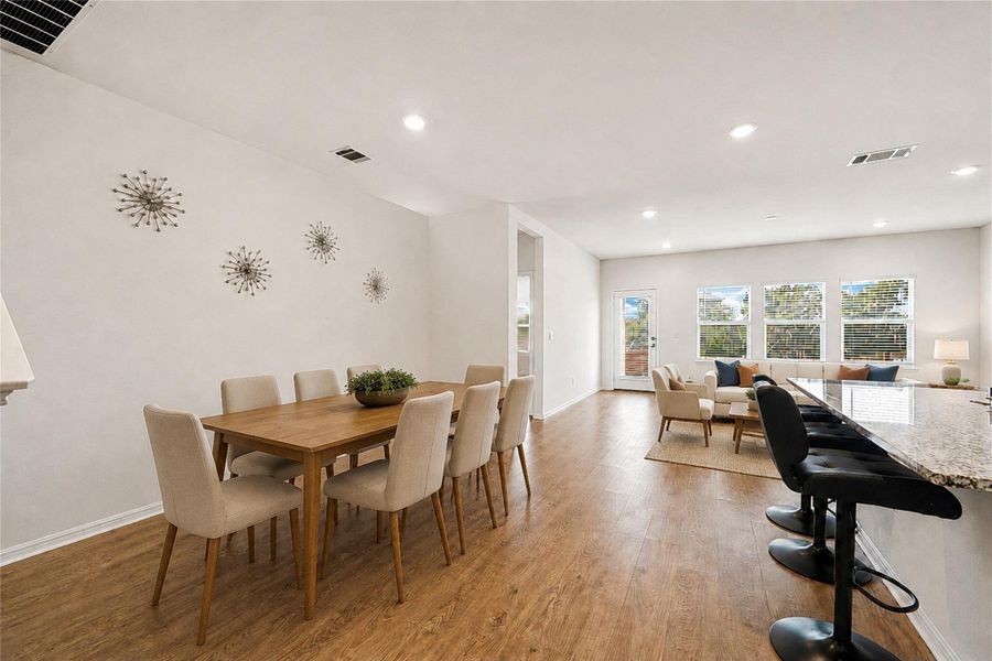 Living area presents versatile dining and relaxation areas, united by warm wood flooring.