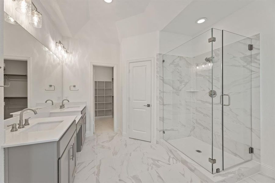 Bathroom featuring a shower with door, vanity, and vaulted ceiling