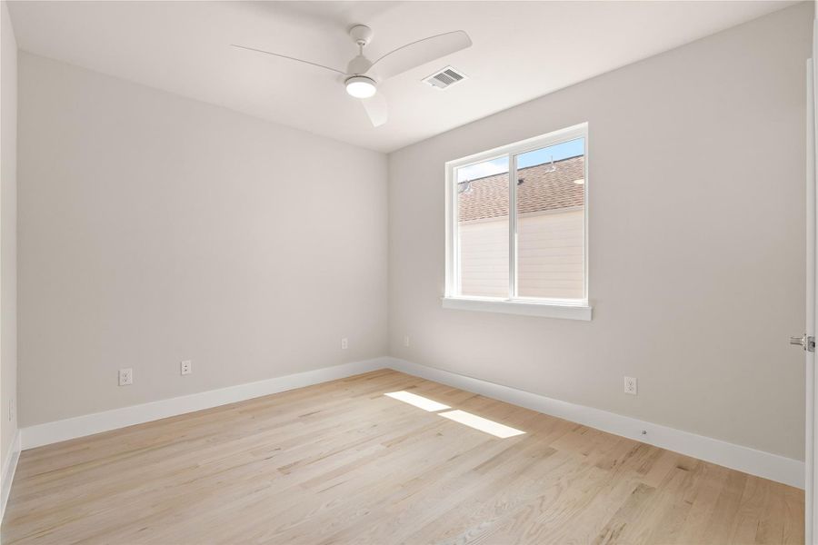 Secondary bedroom with tall windows, ceiling fan and clean architectural lines.