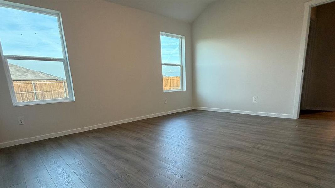 Spare room featuring lofted ceiling and dark wood-style flooring