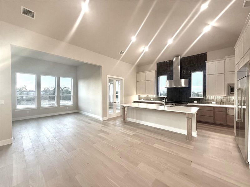 Kitchen with white cabinetry, healthy amount of natural light, a breakfast bar, an island with sink, and vaulted ceiling