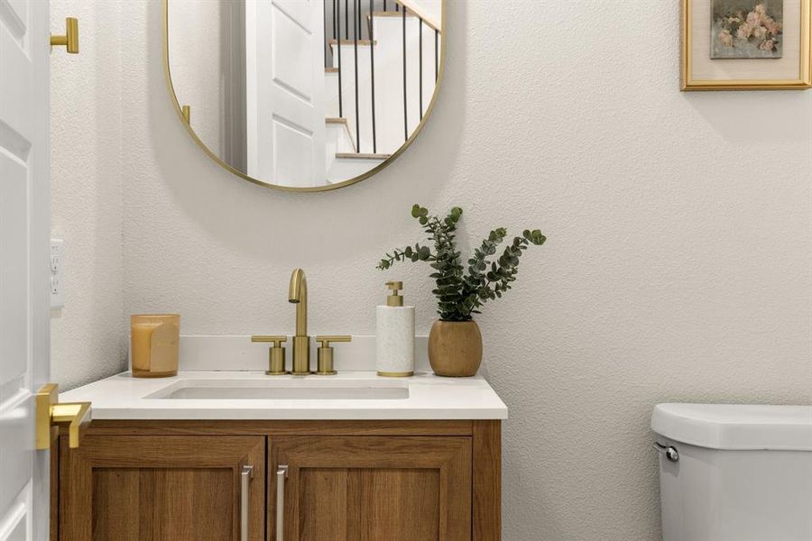 Bathroom with a textured wall, vanity, and toilet