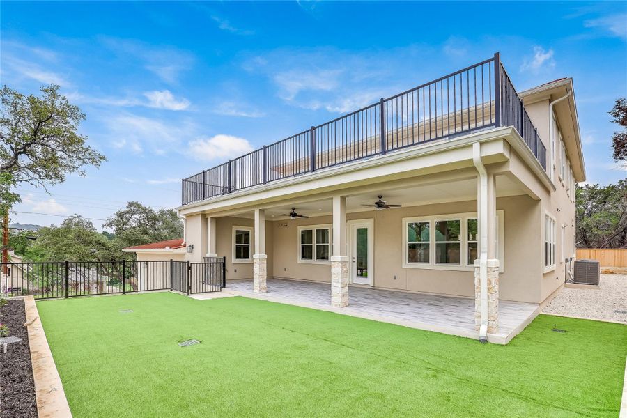 Rear view of house featuring ceiling fan, a patio area, a balcony, a yard, and central AC unit