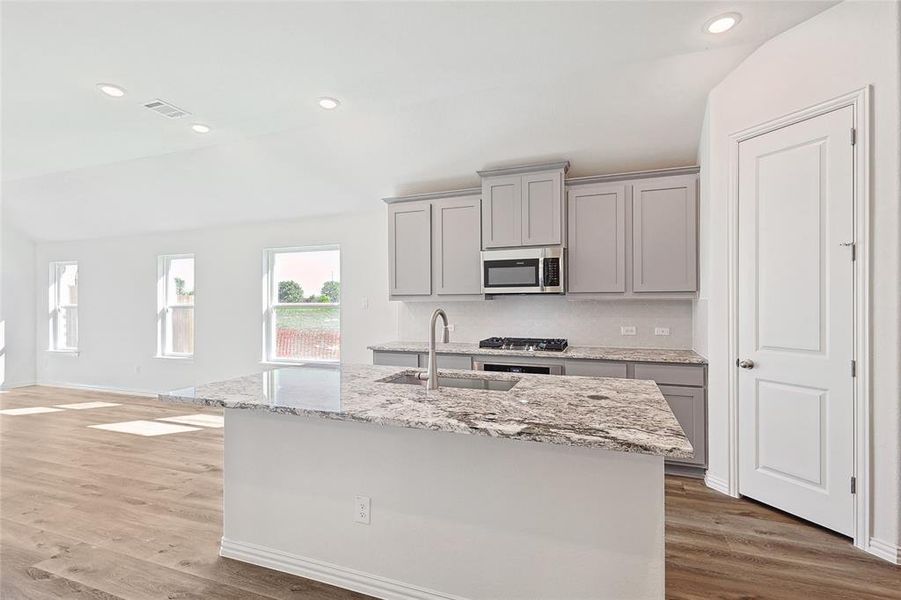 Kitchen with hardwood / wood-style flooring, a kitchen island with sink, sink, gray cabinetry, and stainless steel appliances