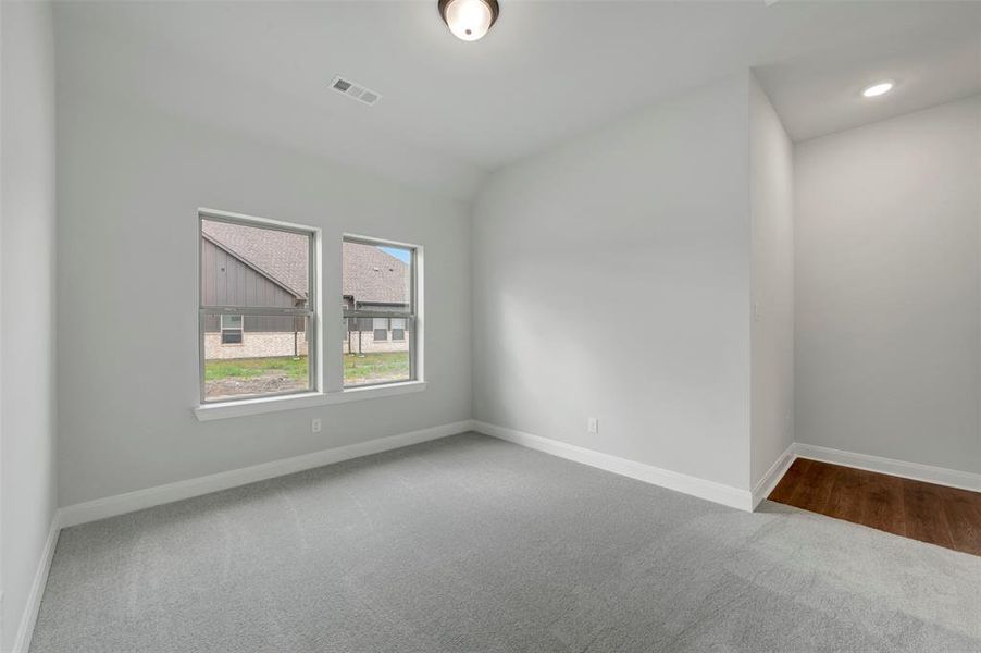 Unfurnished room featuring light carpet and lofted ceiling