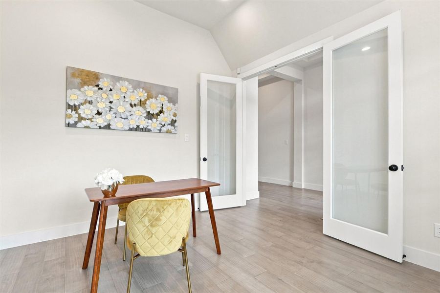 A quiet office space offers ample natural light and a seamless transition to other areas through stylish glass-paned doors.