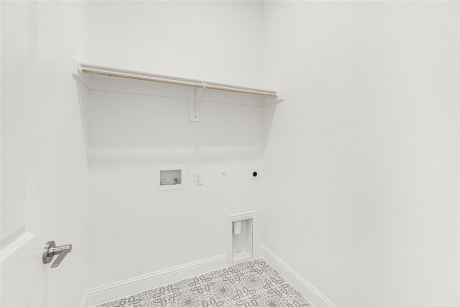 Laundry room with wall shelf, hanging rod, washer hookups, and patterned tile floor Laundry room with wall shelf, hanging rod, washer hookups, and patterned tile floor