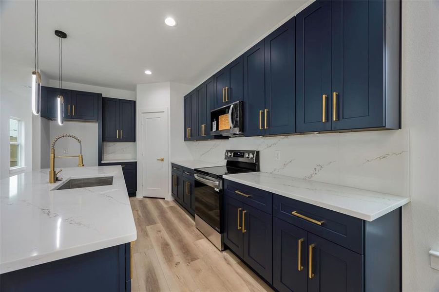 Kitchen featuring decorative light fixtures, sink, decorative backsplash, stainless steel range with electric stovetop, and light wood-type flooring