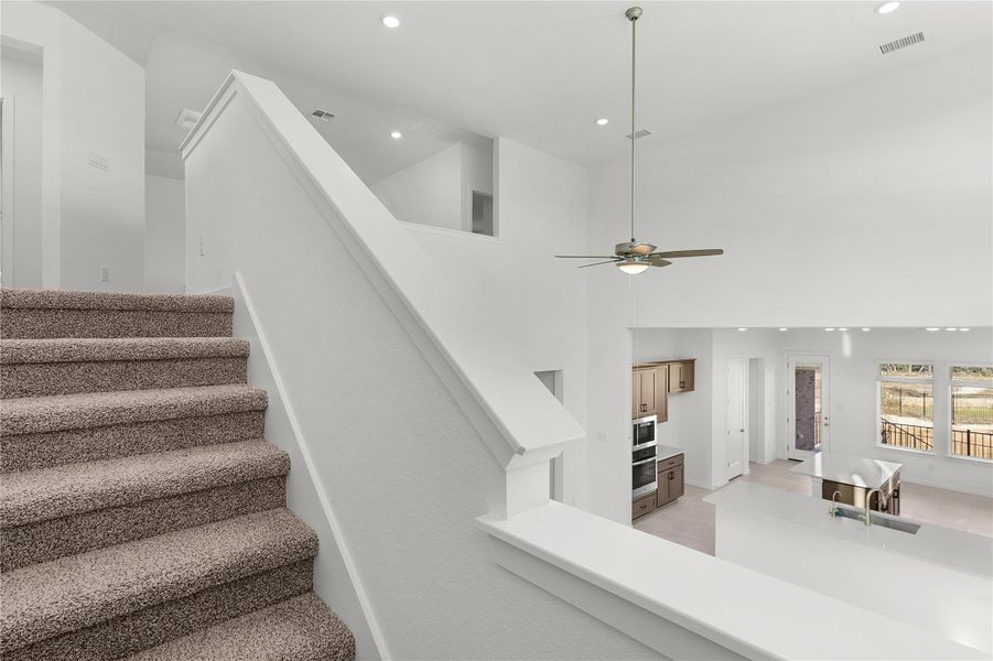 Stairway featuring recessed lighting, a ceiling fan, a high ceiling, and baseboards