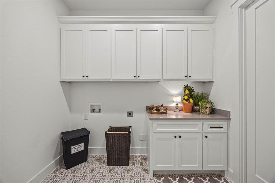 Clothes washing area with electric dryer hookup, cabinets, hookup for a washing machine, and light tile patterned floors