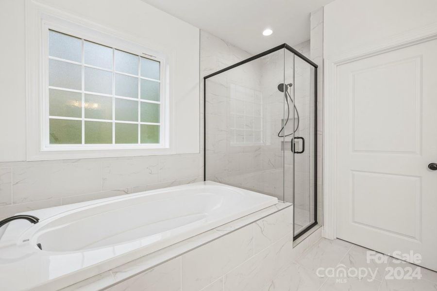 Spa-like primary bathroom with soaking tub and tile shower