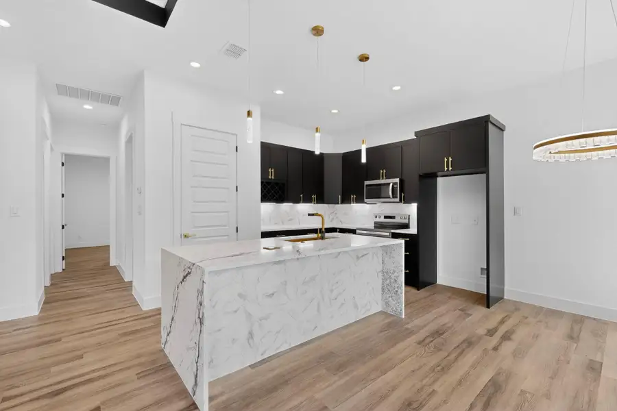 A gourmet kitchen showcasing an expansive island and sleek black cabinetry.