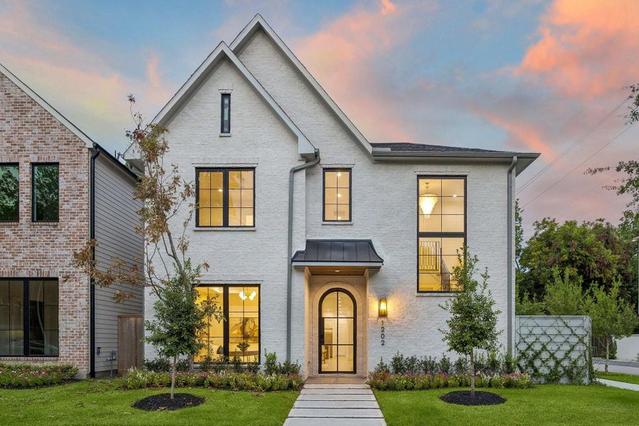 This home showcases a refined modern European-inspired design with clean lines, timeless materials, and elegant curb appeal. There is a Slurry Finished Brick Exterior with Hardi-Plank, a series of Steep Front-Facing Gables, Dramatic two-story picture window on the right side serves as a striking focal point. The front entry features a rounded-top Iron glass door tucked beneath a dark standing-seam metal awning, creating a welcoming and elegant entrance. Elevator Capability, Dramatic Open Staircase & More