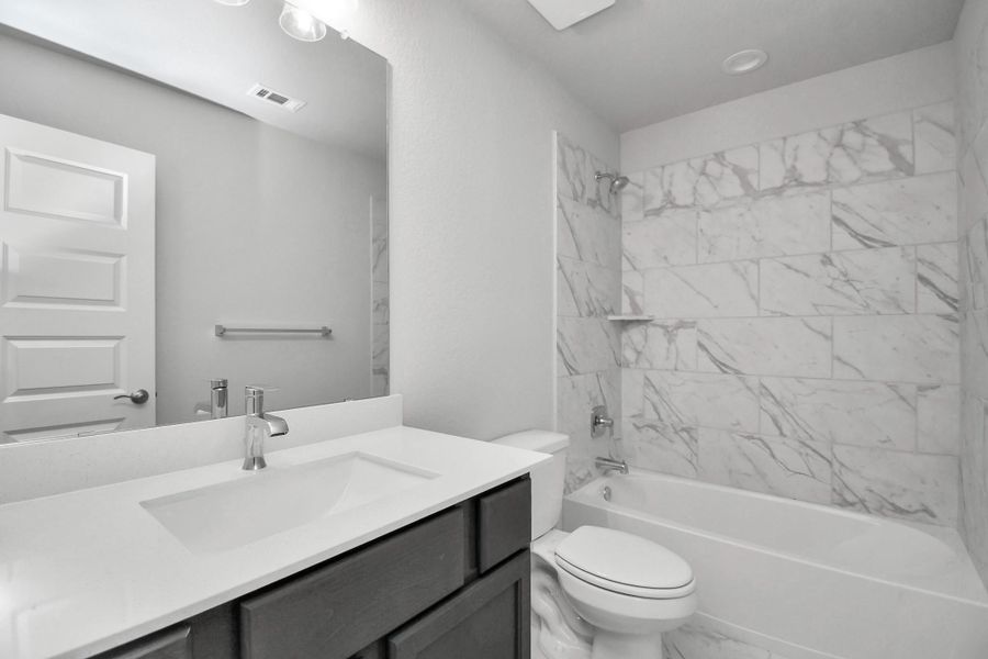 Secondary bath features tile flooring, bath/shower combo with tile surround, light stained wood cabinets, beautiful light countertop. Secondary bath features tile flooring, bath/shower combo with tile surround, light stained wood cabinets, beautiful light countertop. Sample photo of completed home with similar floor plan. Actual colors and selections may vary.