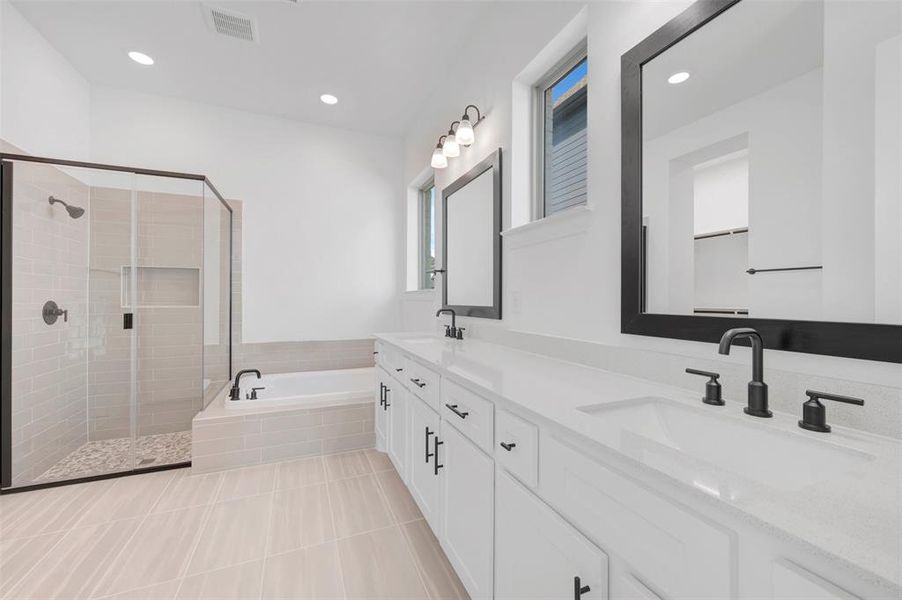 Contemporary bathroom featuring a spacious walk-in shower with pebble tile flooring and a built-in niche, a large soaking tub, a dual vanity with quartz countertops, framed mirrors, and matte black fixtures Contemporary bathroom featuring a spacious walk-in shower with pebble tile flooring and a built-in niche, a large soaking tub, a dual vanity with quartz countertops, framed mirrors, and matte black fixtures