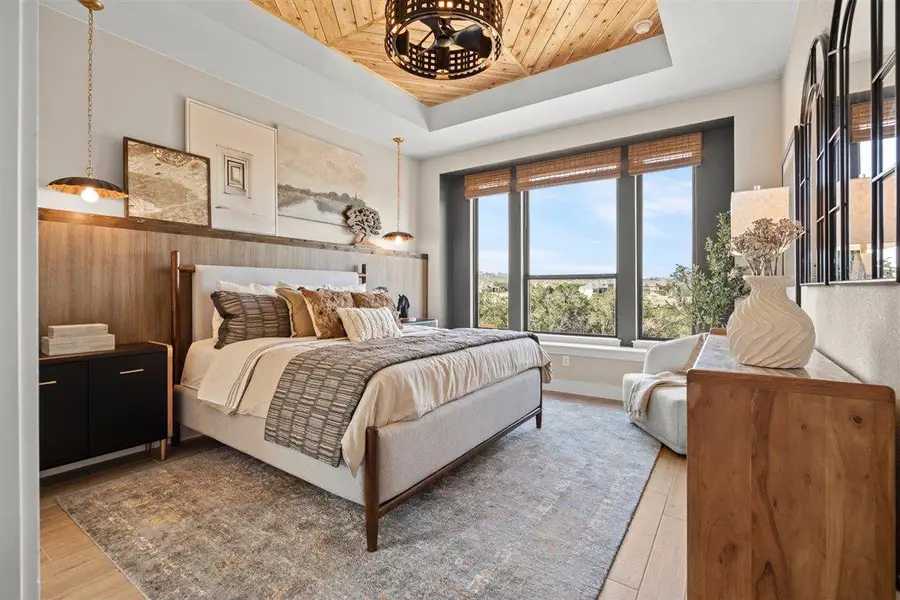 Bedroom with light wood finished floors and a raised ceiling