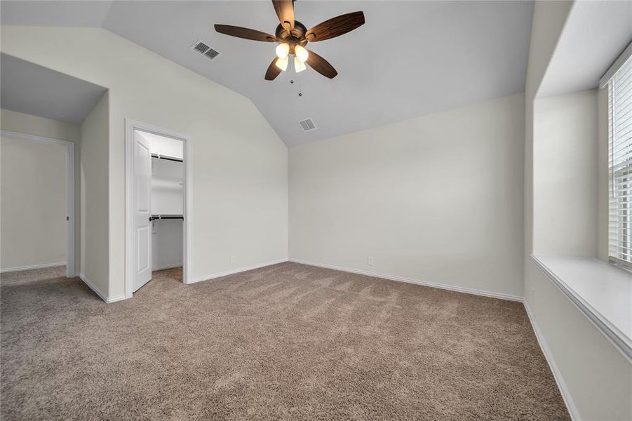 Unfurnished bedroom with light colored carpet, lofted ceiling, a spacious closet, and ceiling fan Unfurnished bedroom with light colored carpet, lofted ceiling, a spacious closet, and ceiling fan