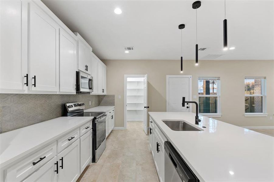 Kitchen featuring white cabinetry, sink, decorative light fixtures, appliances with stainless steel finishes, and light wood-type flooring