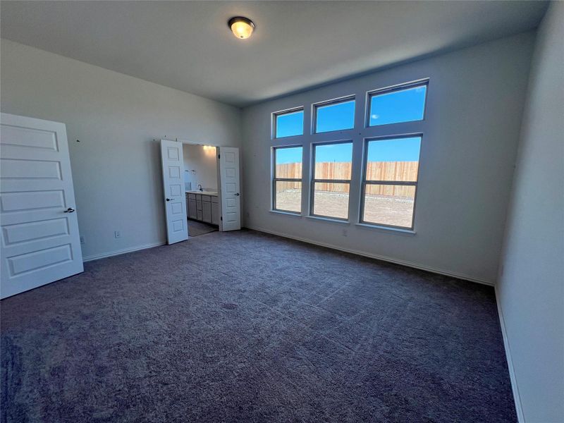 Unfurnished bedroom featuring dark carpet and ensuite bath