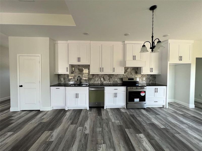 Kitchen featuring a sink, dark countertops, appliances with stainless steel finishes, and white cabinets