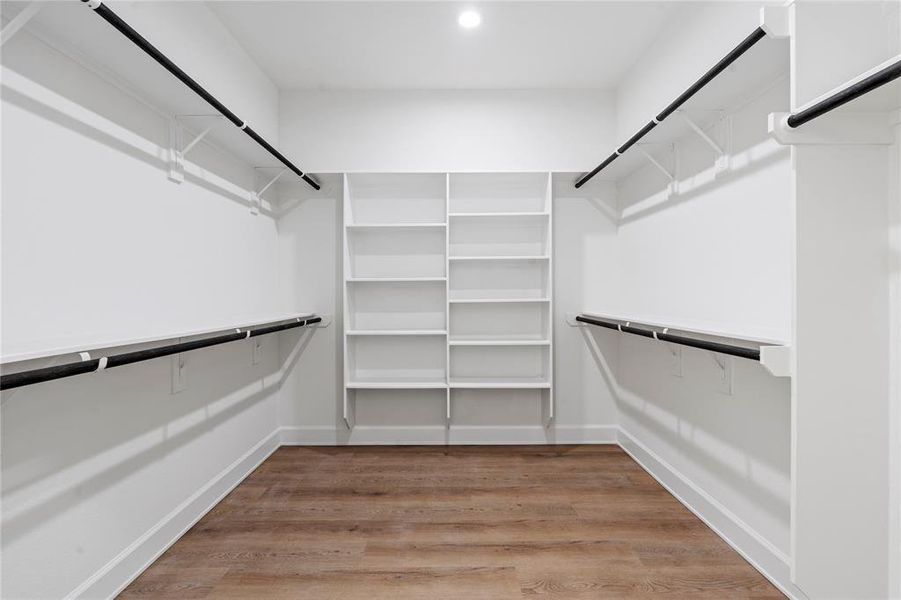 Spacious walk-in closet featuring ample hanging space and built-in shelving, perfect for organized storage. Spacious walk-in closet featuring ample hanging space and built-in shelving, perfect for organized storage.