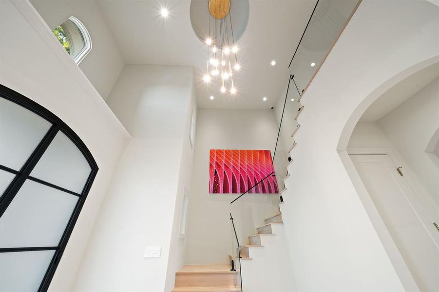 This striking staircase to the second floor will WOW you with its custom architectural railing and the chandelier from Arteriors.
