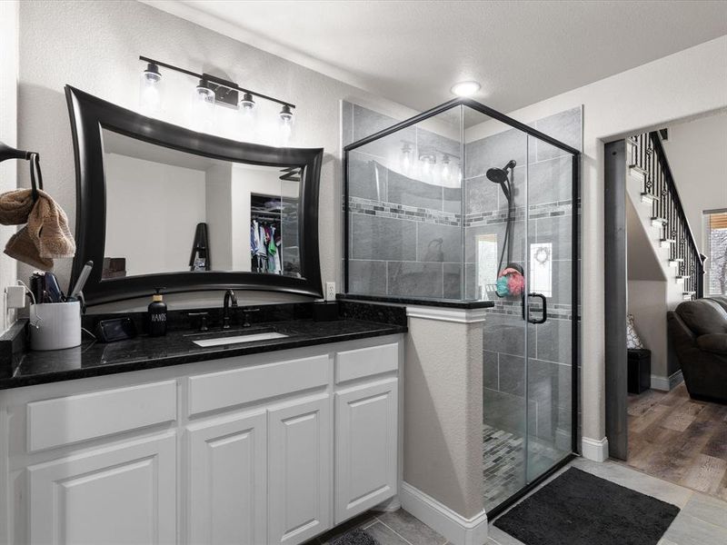 Bathroom with a shower stall, vanity, and baseboards