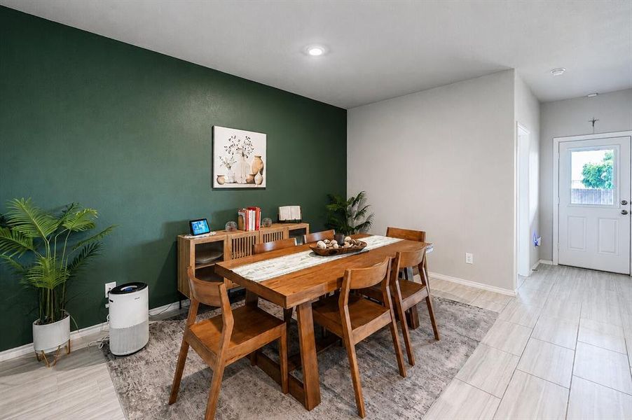 Dining area featuring a dark green accent wall, recessed lighting, and light-toned wood-finish flooring